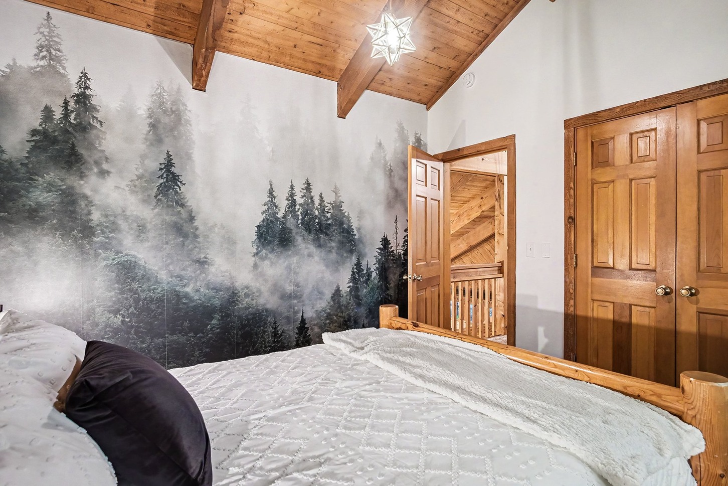 Bedroom with forest mural wall and vaulted wood ceiling