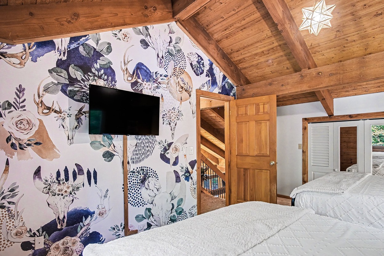 Bedroom with floral accent wall and wall-mounted TV