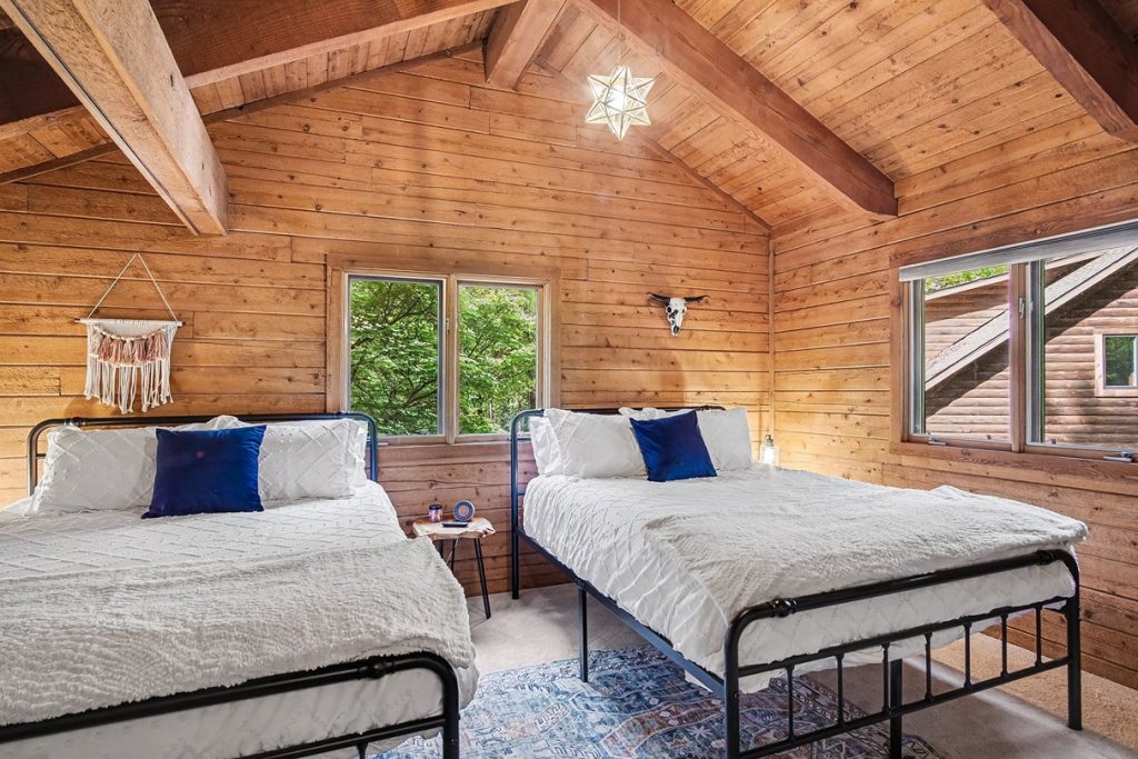 Loft bedroom with two beds and a vaulted wood ceiling
