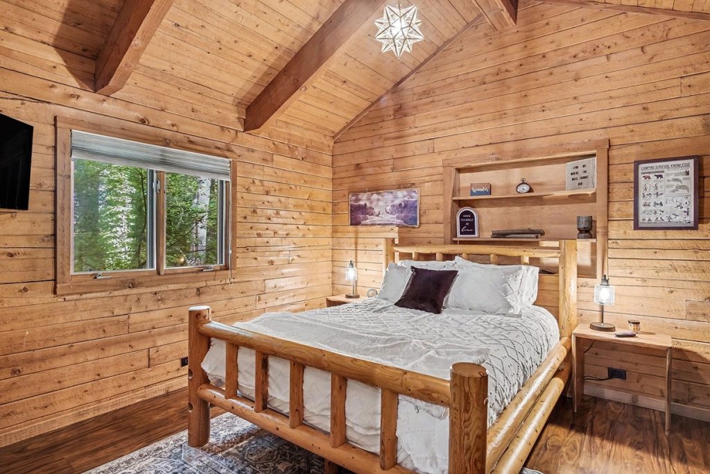 Rustic bedroom with wood bed frame and forest views