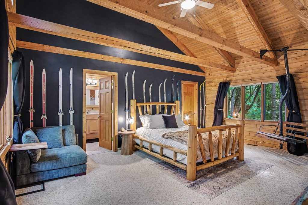 Primary bedroom with ski decor, vaulted wood ceiling, and sitting area