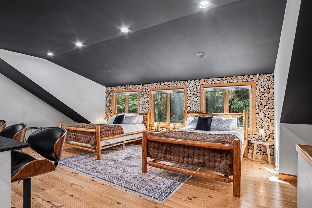 Cabin guest suite with two beds, forest views, and bar seating