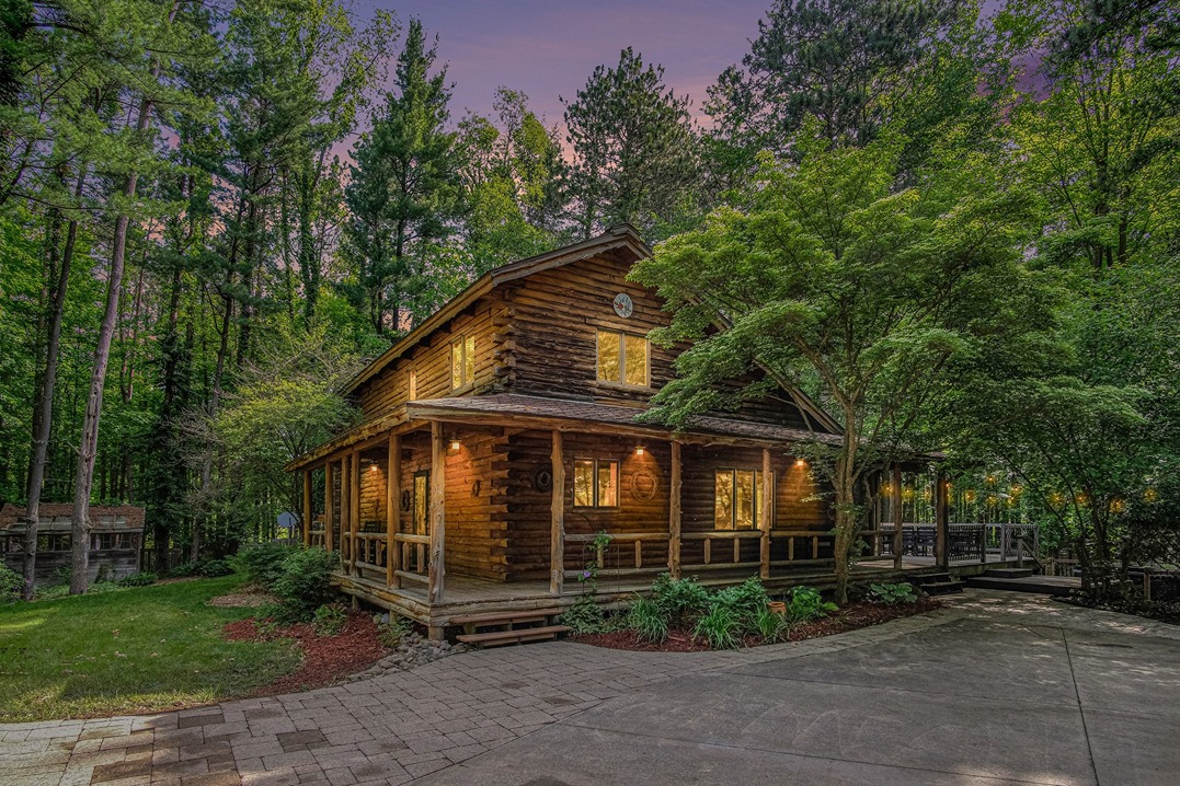 Log cabin exterior glowing at dusk among trees